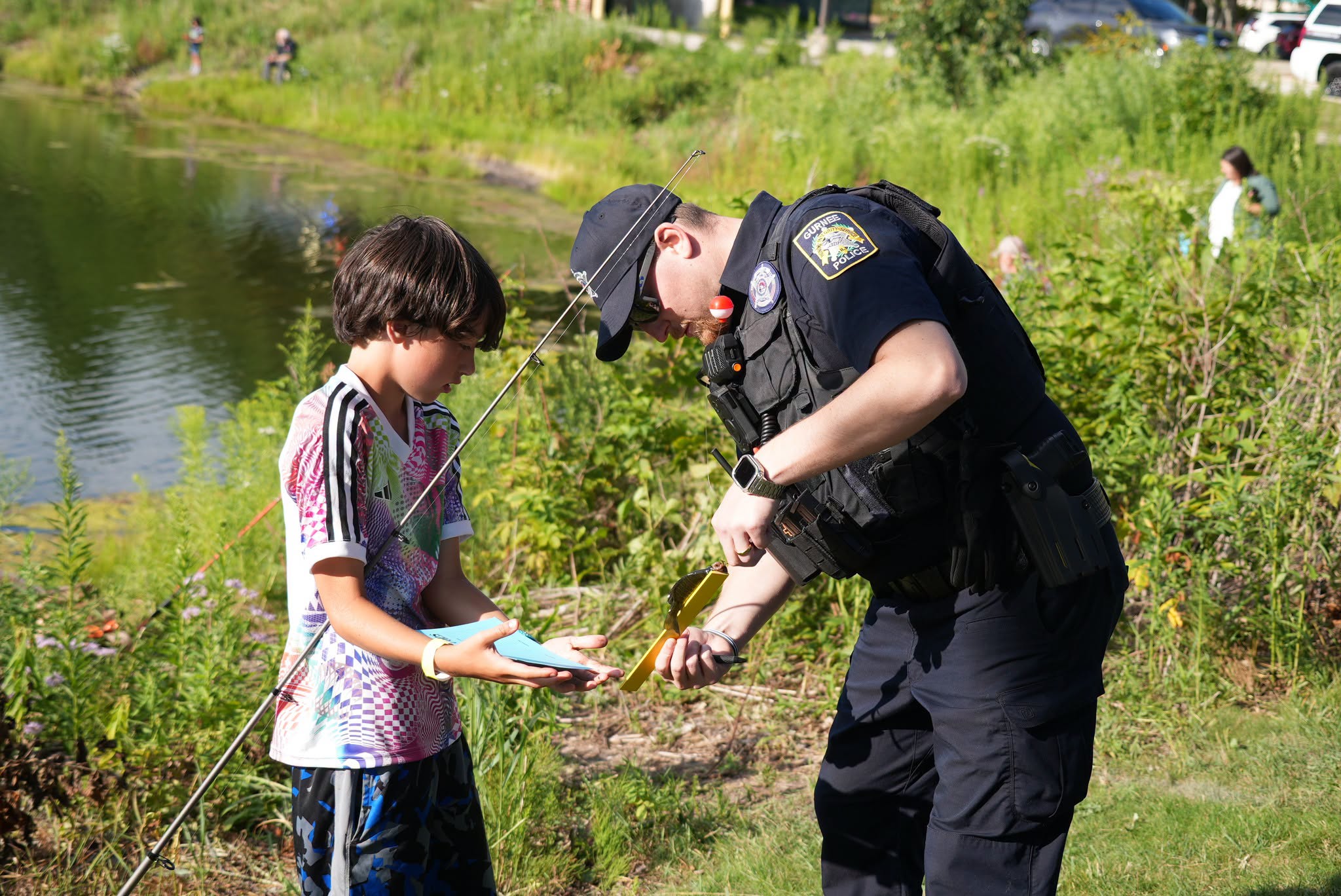 Police officer helping a child baiting the hook at the Cops & Bobbers event. Photo courtesy of Gurnee Park District.